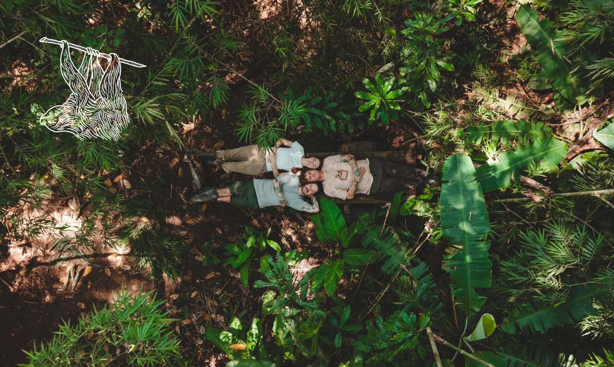 Aerial view of two people lying on damp ground surrounded by lush tropical vegetation and banana plants.