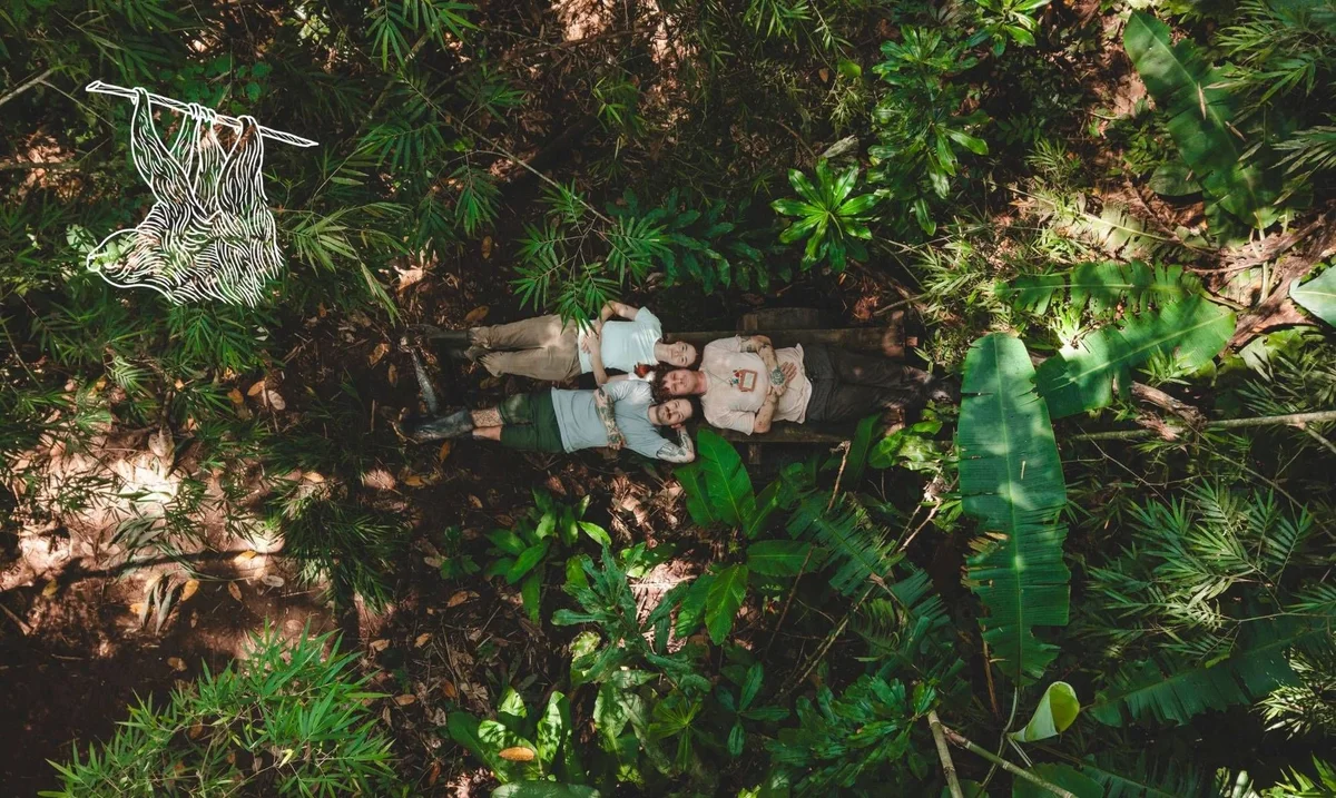 Aerial view of two people lying on damp ground surrounded by lush tropical vegetation and banana plants.